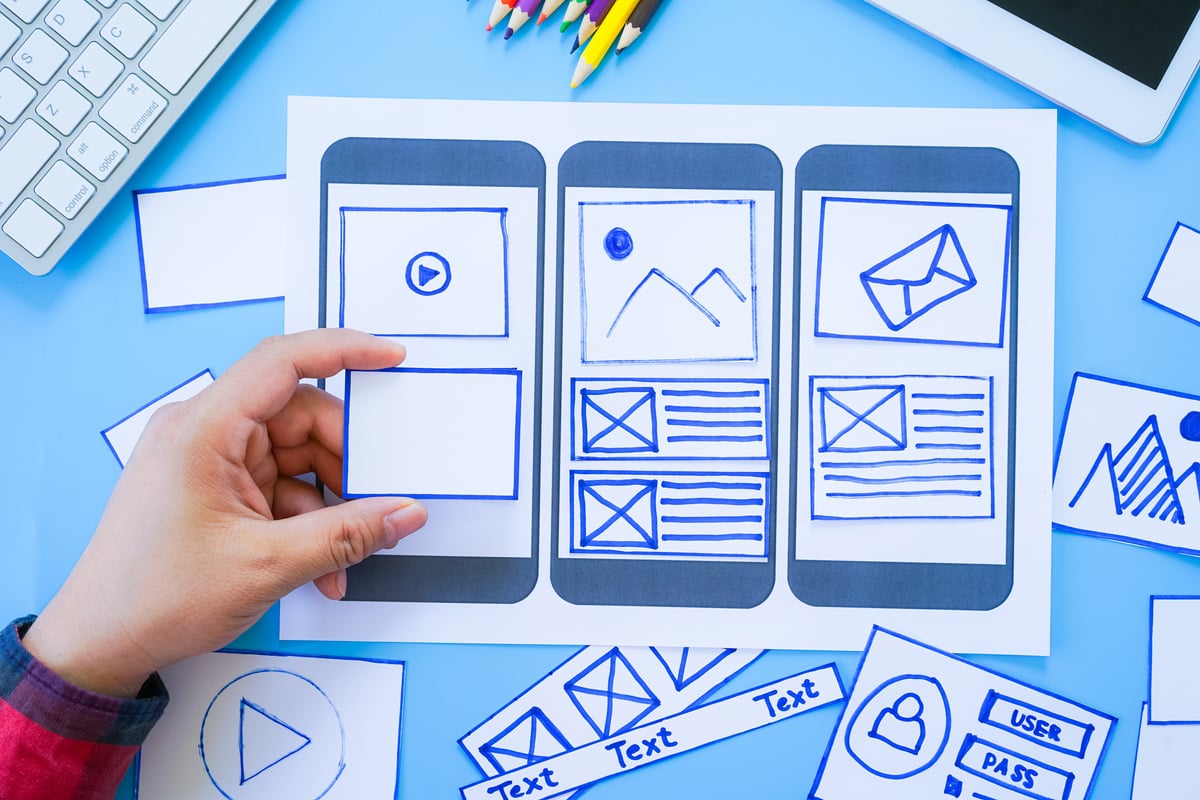Website development team sketching wireframe layout design for responsive web content, two UI/UX front end designers in office